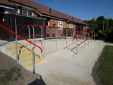 red powder coated handrail system places in pedestrian area. Disability Access Ramp access up to residential area